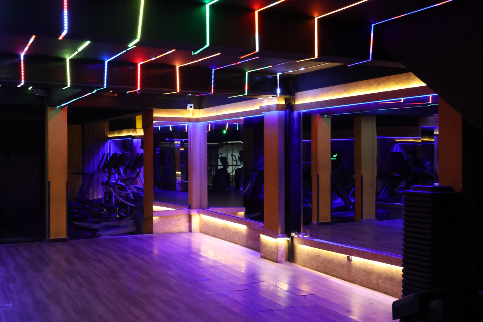 Salón de clases grupales de LinkGym Soacha, con techo de neón de colores y espejos